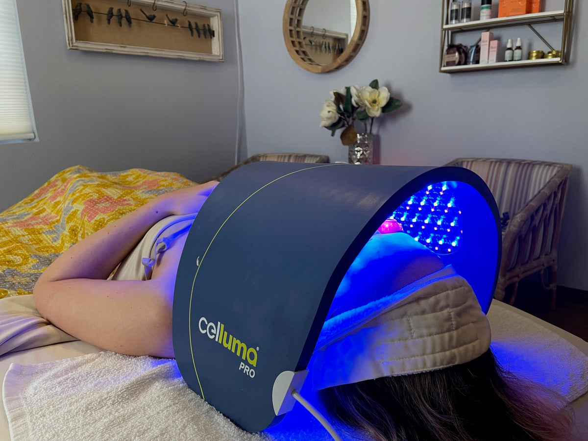 Person lying under a Celluma Pro LED light therapy device in a bedroom setting.